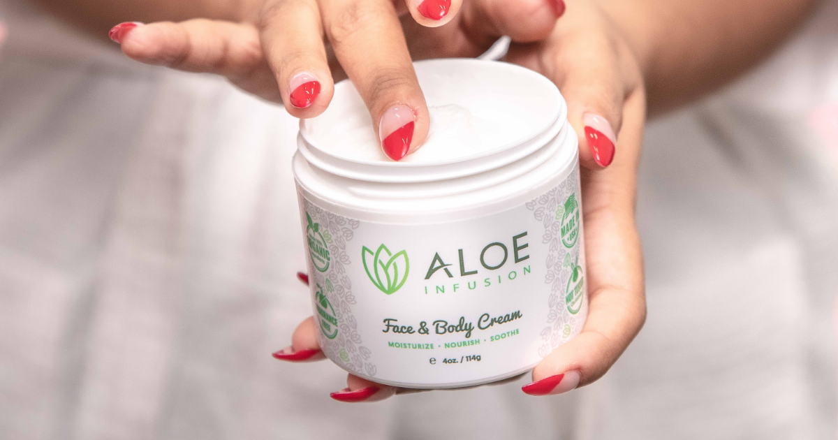 Close-up of a person's hands holding a white jar of "ALOE INFUSION" Face & Body Cream.