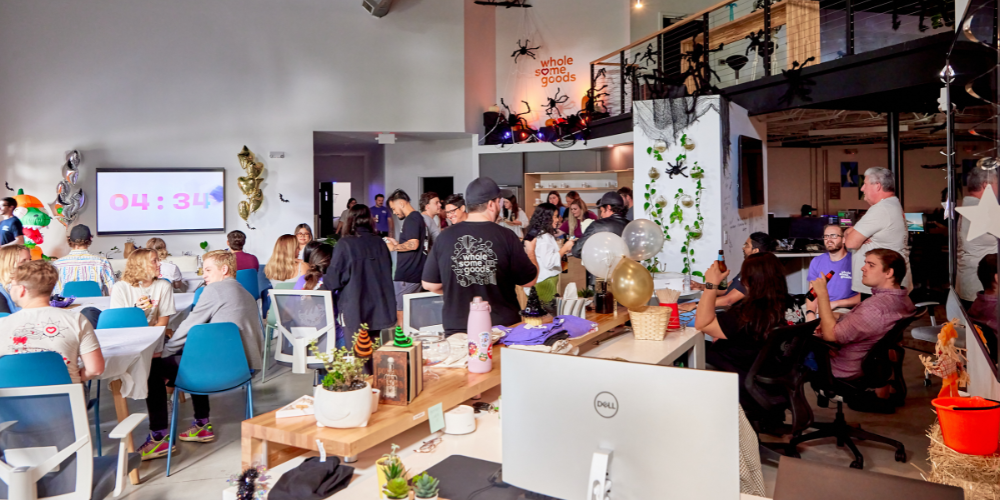 Festive Halloween celebration in a modern office space with employees socializing.