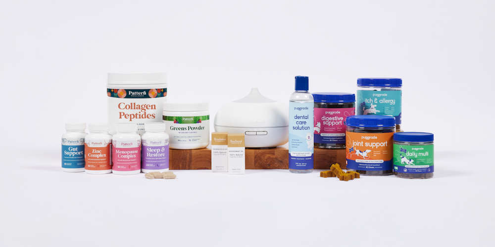 wholesome-goods-blog (11) A full product lineup from Wholesome Goods brands, including Pattern Wellness supplements, PupGrade dog health soft chews and solutions, and a Rooted Beauty essential oil diffuser, all displayed against a clean white background with product samples in front.