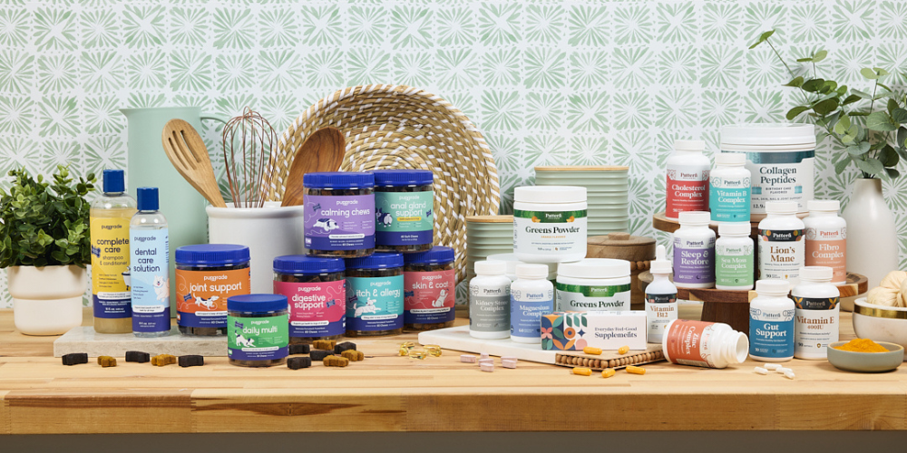 A wholesome kitchen countertop display featuring PupGrade dog supplements and Pattern Wellness human wellness products, including calming chews, joint support, and greens powder—illustrating a unified standard of care for pets and their owners.