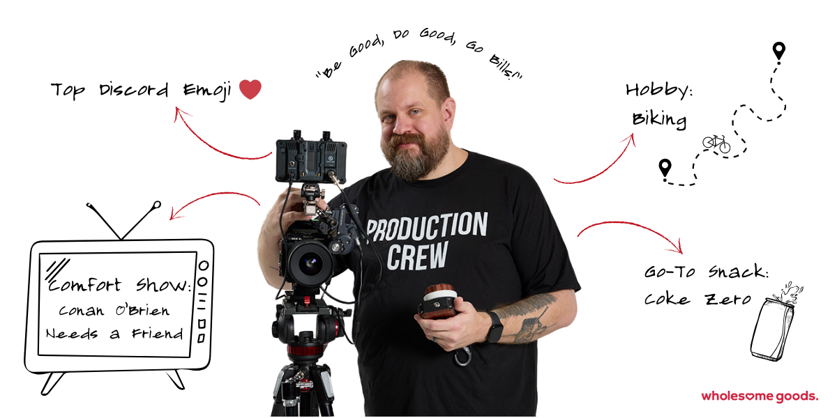 Senior Media Specialist Dave operating a professional camera on tripod, wearing a “Production Crew” shirt at Wholesome Goods.