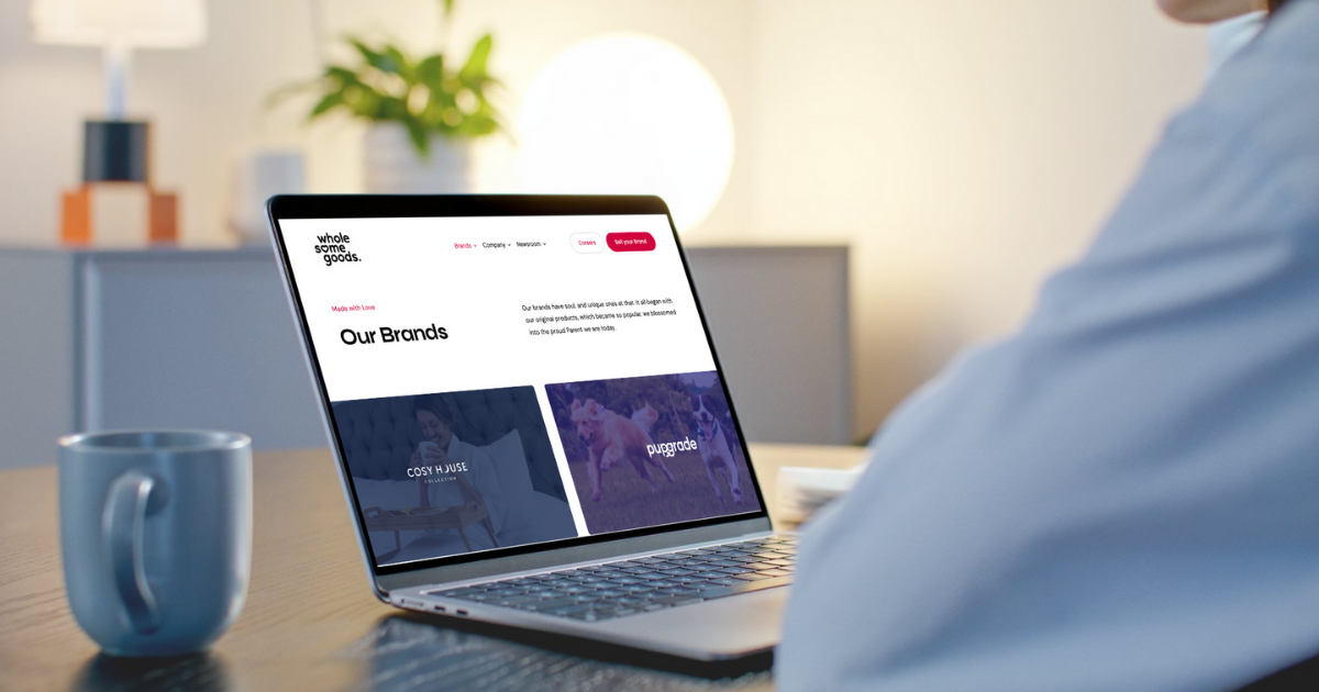 a person sitting a desk with a laptop with the Wholesome Goods Brand page open